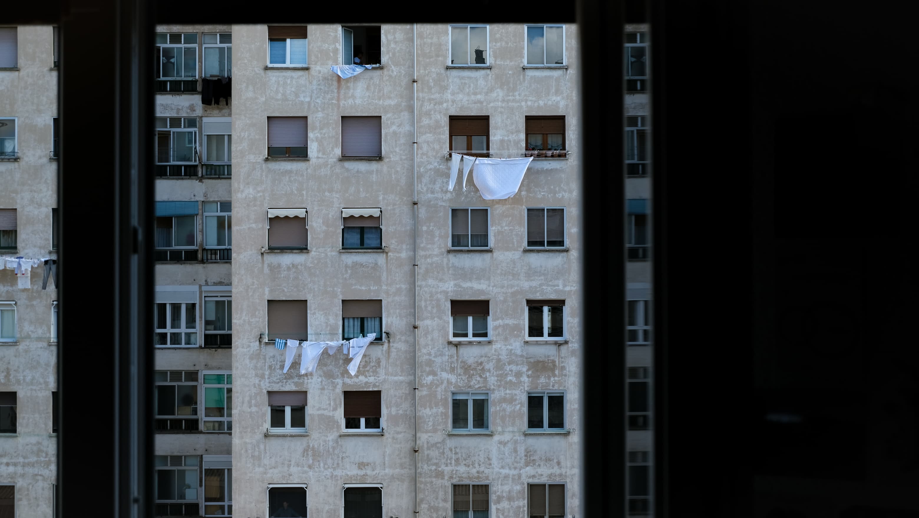 Laundry drying on the balconies of an apartment block, framed by a window