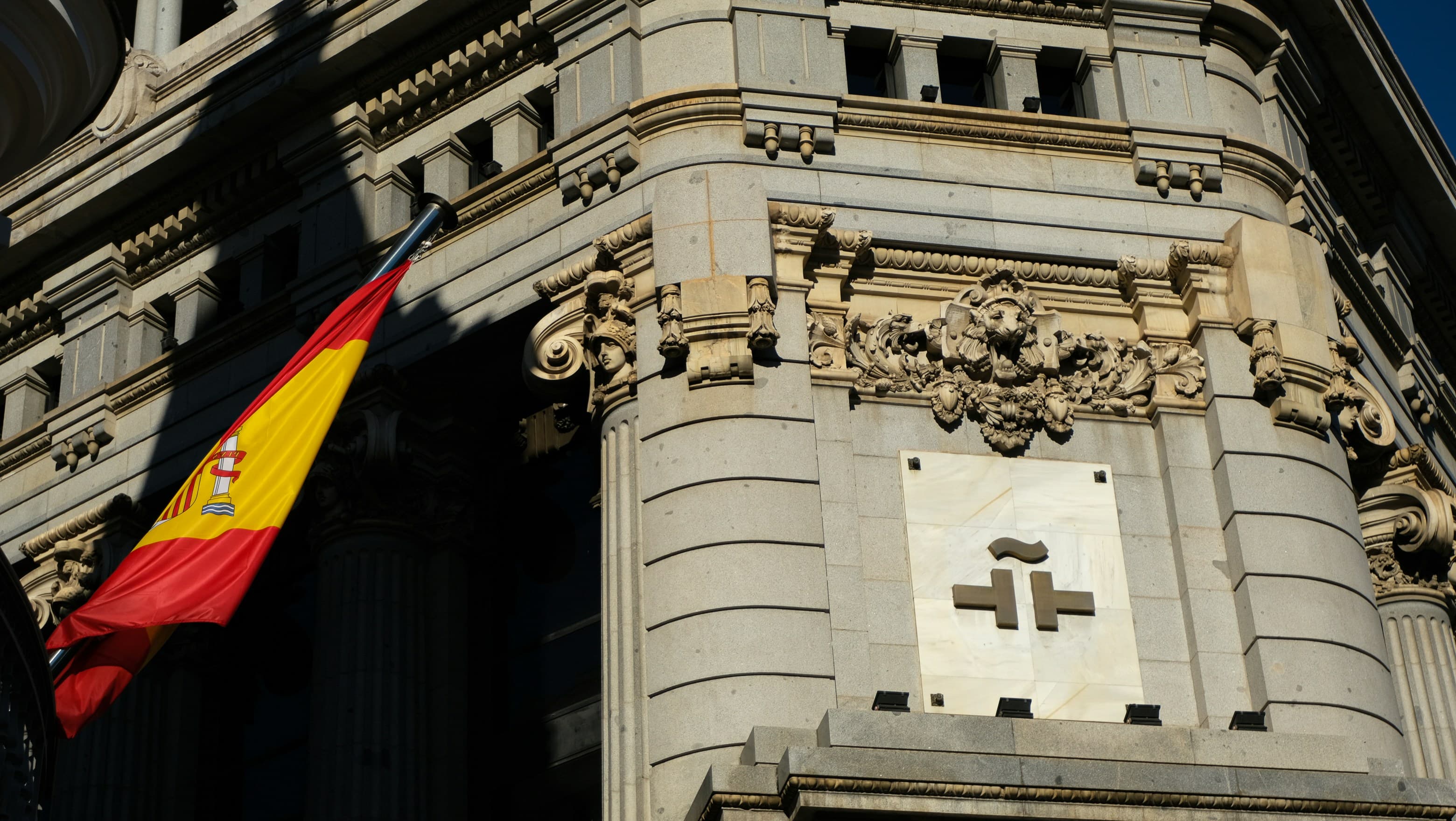 A Spanish flag hanging from the carved stone corner of a bank