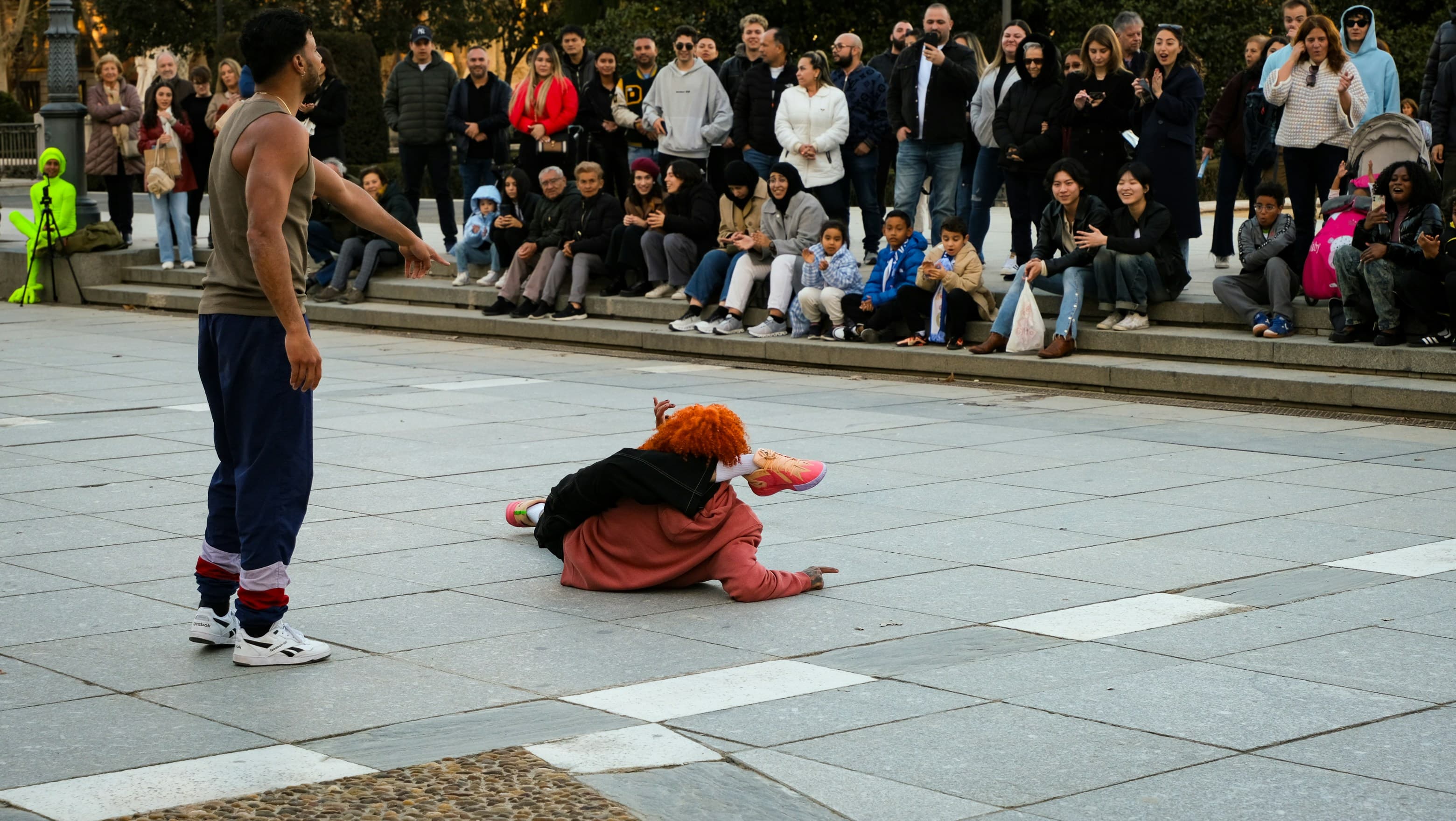Street performers working a crowd seated around a paved square