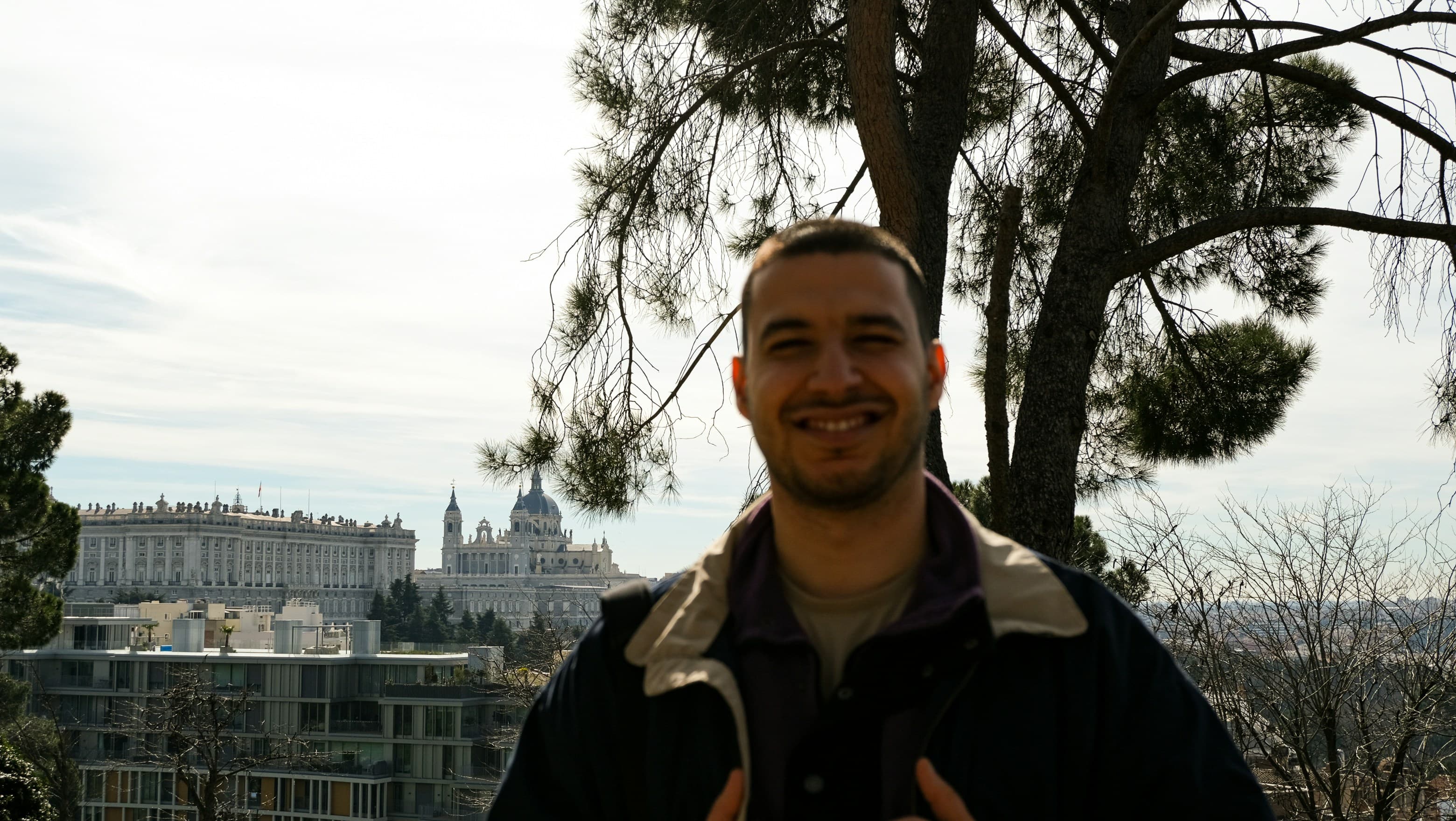 A portrait under a pine, a cathedral dome on the hillside behind
