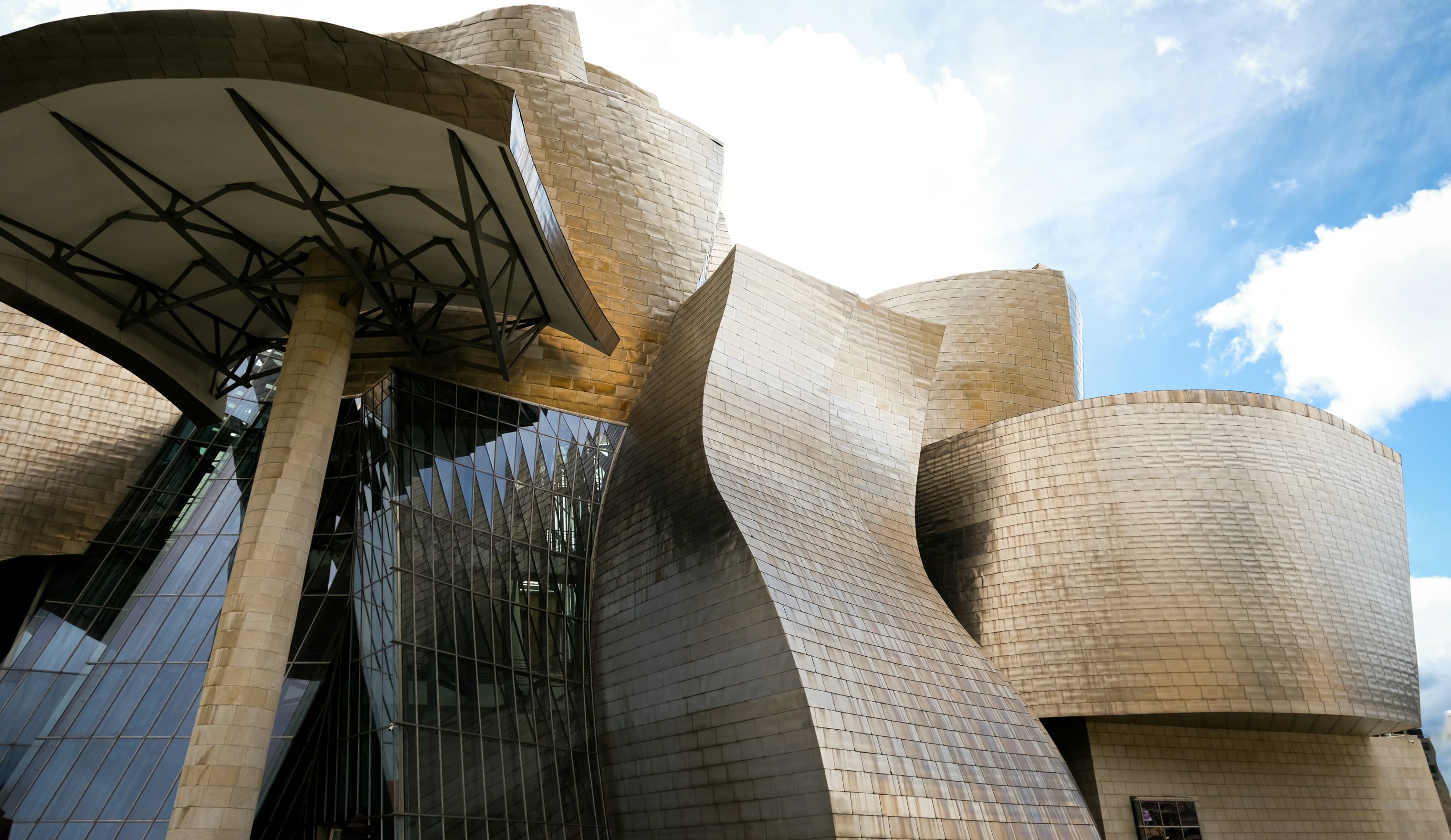 Titanium panels of a museum curving against a blue sky