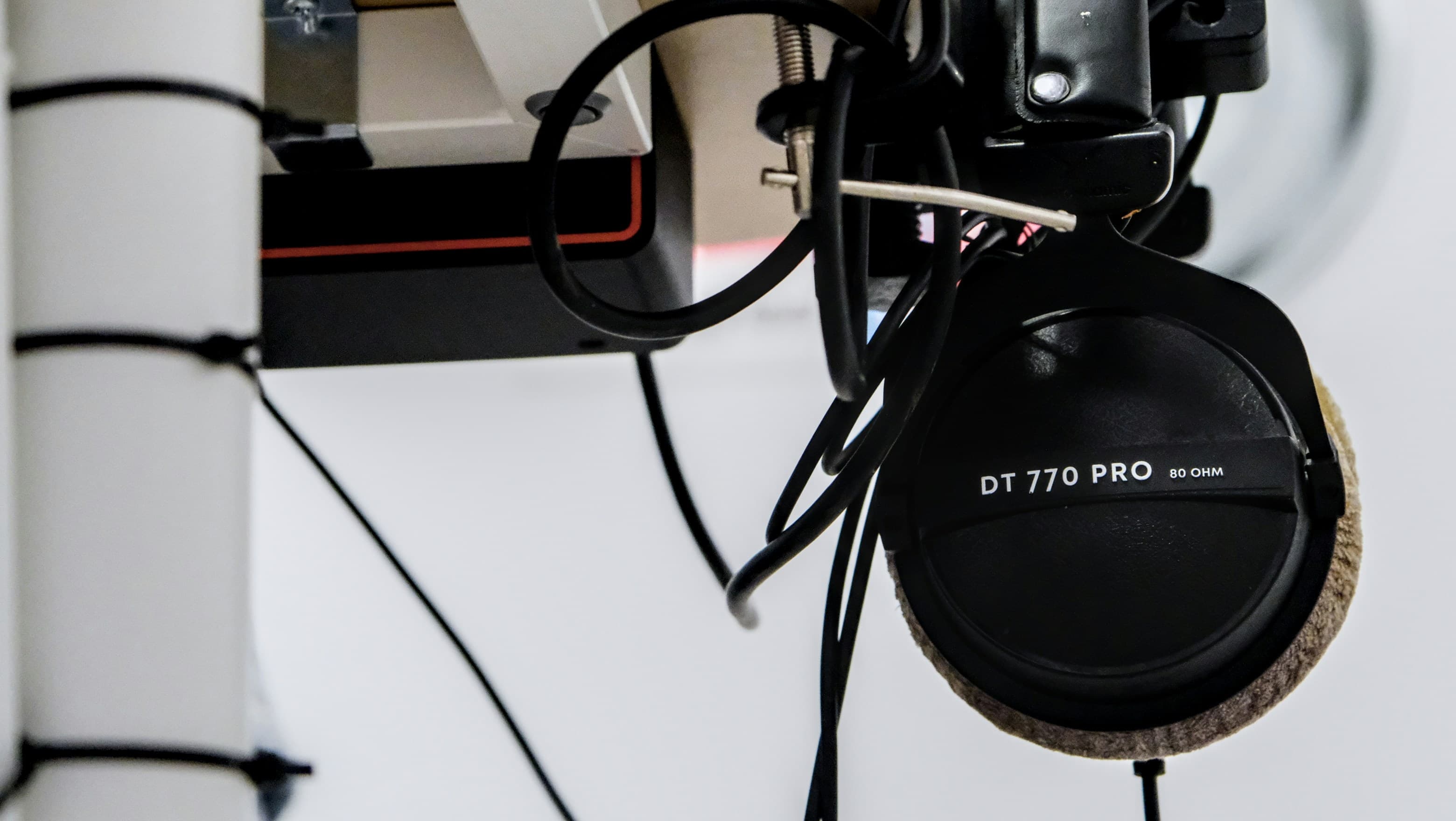 A DT 770 Pro earcup marked 80 ohm, hanging under a desk among cable runs
