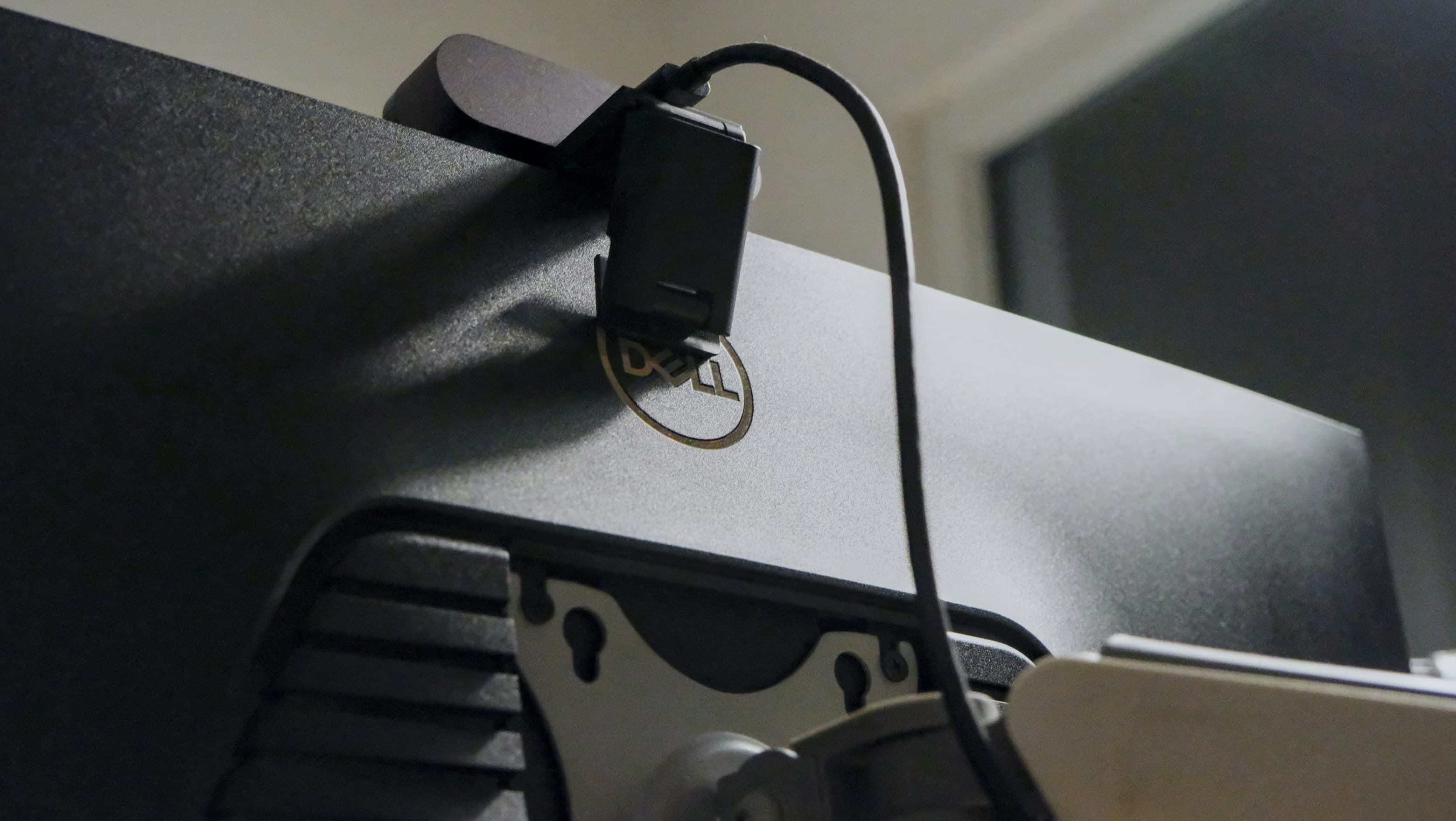 The back of a monitor with a webcam clamped over the top edge and its cable running down