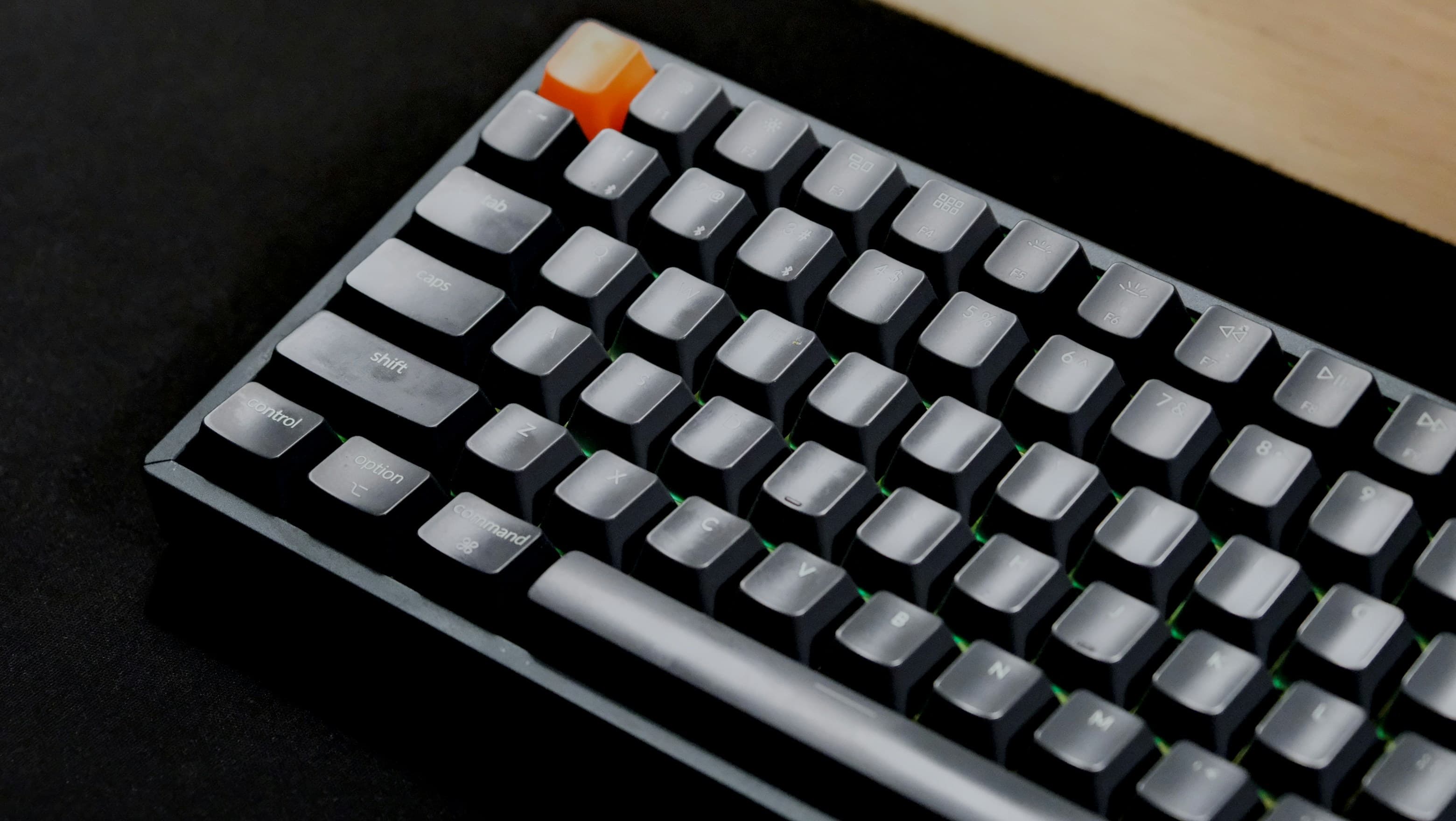 The top left of a mechanical keyboard, grey keycaps with a single orange one in the top row