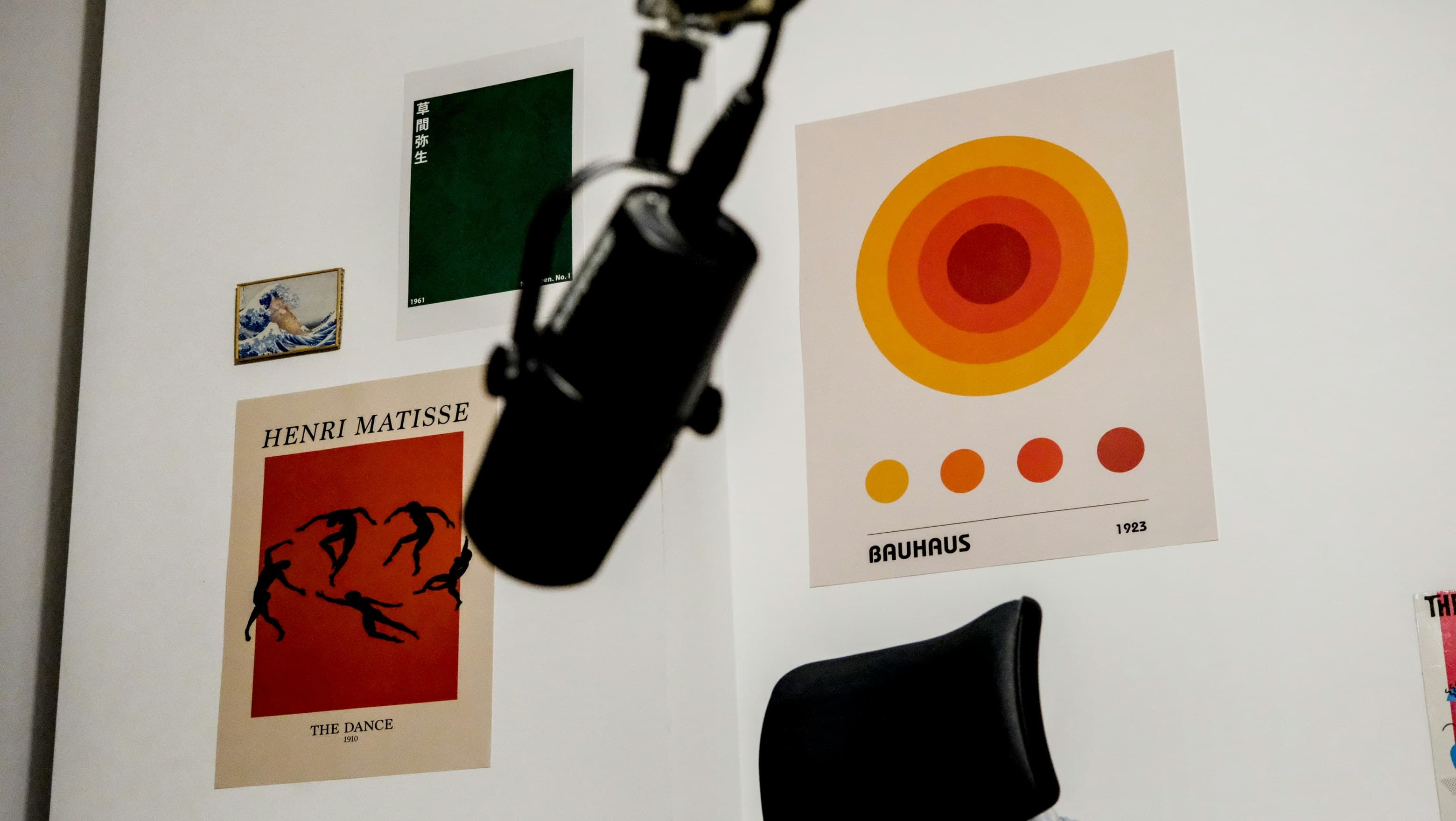 Four prints arranged on a white wall: a green Kusama poster, a small framed Great Wave, Matisse's The Dance and a Bauhaus print